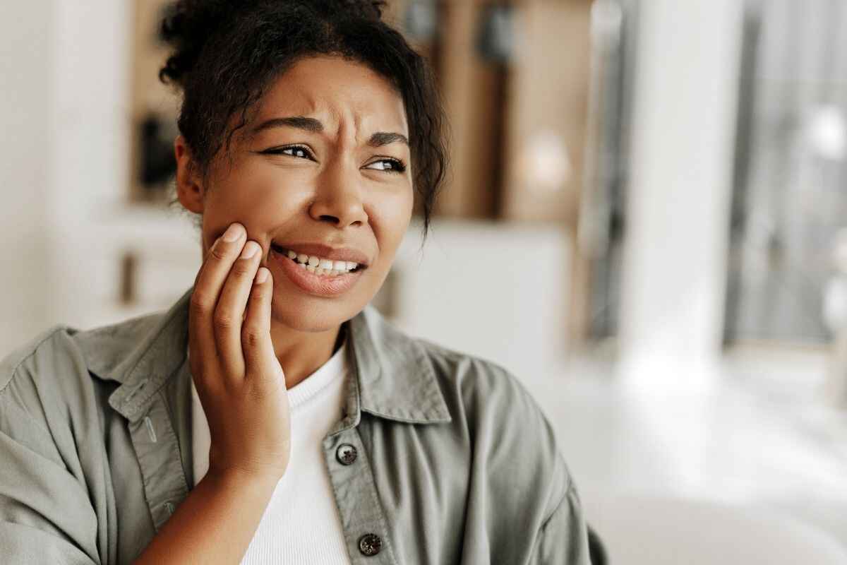Woman holding her jaw in pain while biting down, indicating dental discomfort